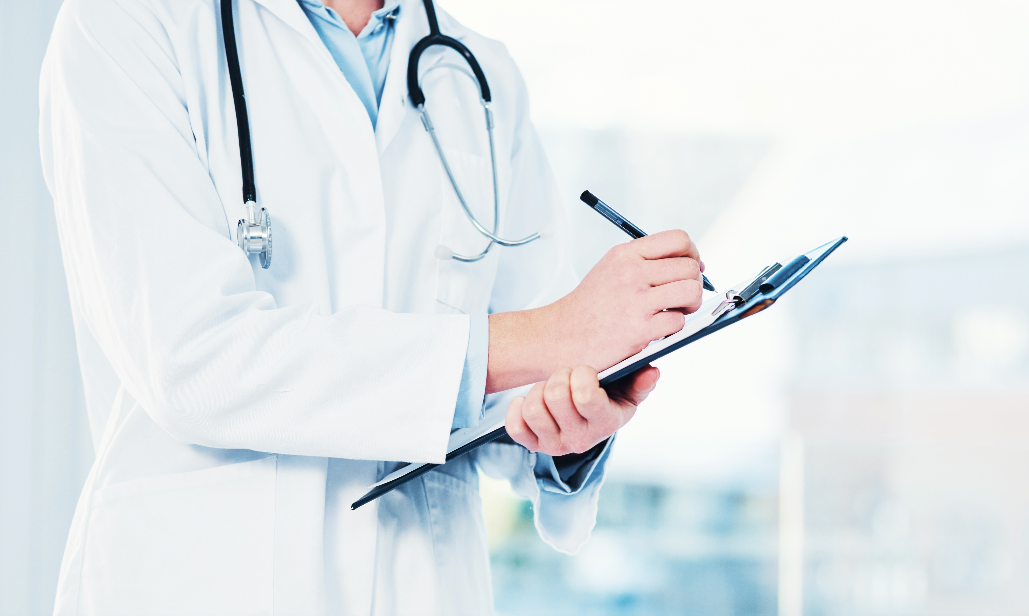 Medico che prende appunti su una cartella medica.